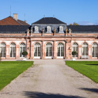 Schloss und Schlossgarten Schwetzingen - Garten - Nördlicher Zirkelbau - Von Südwest - Blick auf den zentralen Teil des nördlichen Zirkelbaus (Gesamter Bau: Länge Bogen ca. 175 Meter, Breite zwischen ca. 11 und 18 Meter, 51 Achsen, 5 Pavillons, 4 Zwischenbauten; Architekt: Alessandro Alessandro Galli da Bibiena (1686-1748), Bauleitung: zuerst Guillaume d’Hauberat (1680–1749), dann Nicolas de Pigage (1723-1796); Bauzeit: 1748-1750) (aufgenommen im Oktober 2024, am frühen Nachmittag)