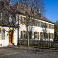 Schloss und Schlossgarten Schwetzingen - Sonstige Bauten - Altes Forstamt (Forsthausstraße 11) - Von Nordwest - Blick vom Ende der Forsthausstraße nach Südost auf die Westseite des Alten Forstamtes (rechts); links davon der Verbindungsbau zwischen Forstamt und Palais Ysenburg (Bau: Länge x Breite: ca. 22 x 14 Meter; Geschosse: 3 (inkl. Mansardgeschoss); Fensterachsen: 7; Bauzeit: 1760; erbaut als Haus des kurfürstlichen Oberjägermeisters; Verbindung mit dem Palais Ysenburg: 1775; Architekt: unbekannt) (aufgenommen im April 2025, am späten Nachmittag)