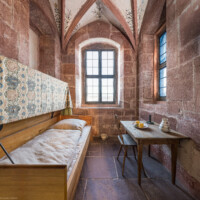 Schloss und Schlossgarten Schwetzingen - Schloss - Mittelbau - Von innen - 1. Obergeschoss - Appartment des Kurfürsten - Lakaienschlafzimmer - Von Westen - Blick nach Osten in das spätgotische Turmzimmer; Nutzung als Schlafraum für den Kammerlakaien (Zimmer: im Zustand 1521, Teil des Standerkers, Zimmer mit Kreuzrippengewölbe, Gewölbe mit vegetabiler Malerei, Gewölbeschlussstein mit dreiteiligem pfälzischem Wappen, Wände mit Resten von farbiger Renaissancemalerei, Trennwand aus Holz mit Lunettenfenstern zum ersten Vorzimmer) (aufgenommen im Dezember 2025, am Nachmittag)