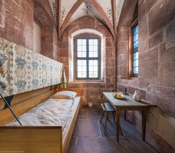 Schloss und Schlossgarten Schwetzingen - Schloss - Mittelbau - Von innen - 1. Obergeschoss - Appartment des Kurfürsten - Lakaienschlafzimmer - Von Westen - Blick nach Osten in das spätgotische Turmzimmer; Nutzung als Schlafraum für den Kammerlakaien (Zimmer: im Zustand 1521, Teil des Standerkers, Zimmer mit Kreuzrippengewölbe, Gewölbe mit vegetabiler Malerei, Gewölbeschlussstein mit dreiteiligem pfälzischem Wappen, Wände mit Resten von farbiger Renaissancemalerei, Trennwand aus Holz mit Lunettenfenstern zum ersten Vorzimmer) (aufgenommen im Dezember 2025, am Nachmittag)