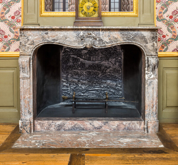 Schloss und Schlossgarten Schwetzingen - Schloss - Mittelbau - Von innen - 1. Obergeschoss - Appartment des Kurfürsten - Zweites Vorzimmer - Südwand - Blick auf den Kamin, das Kaminbesteck und die Kaminplatte (aufgenommen im Dezember 2025, am frühen Nachmittag)